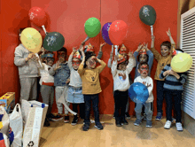 a group of children holding up balloons one of which has a fox on it