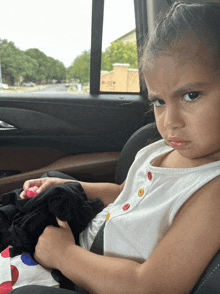 a little girl is sitting in a car seat with a sticker on the window that says ' a ' on it