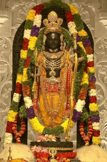 a statue of a deity with a garland of flowers around him