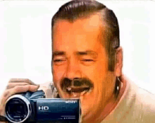 a man with a mustache is laughing while holding a camera that says hd on it