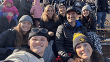 a group of people sitting in a stadium with a man wearing a hat that says ' gs ' on it