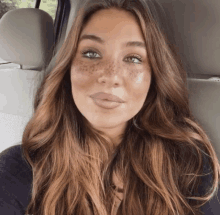 a woman with freckles on her face is sitting in a car