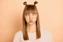 a young woman with two buns on her head is making a funny face .