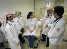 a group of doctors are talking to a patient who is sitting on a bed