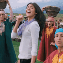 a group of women are carrying baskets on their heads and one of them is wearing a scarf with the letter p on it