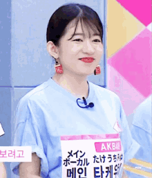 a woman wearing a blue shirt and earrings is smiling