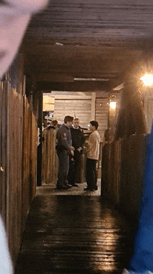 a group of people are standing in a hallway talking