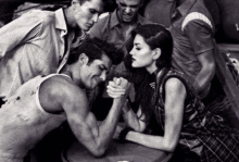 a black and white photo of a man and woman arm wrestling