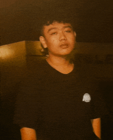 a young man wearing a black t-shirt with a logo on it