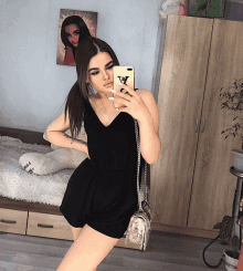 a woman in a black dress is taking a selfie in front of a mirror