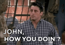 a man in a plaid shirt is standing in front of a window and says `` john , how you doin '? ''