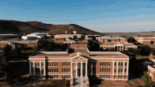 an aerial view of a large brick building with a mountain in the background with the letter s on it