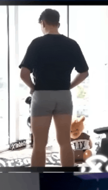 a man in underwear is standing in front of a window