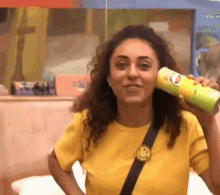 a woman wearing a yellow shirt is holding a can of pringles