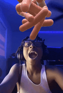 a woman wearing glasses and headphones is holding a bunch of hot dogs in her hands