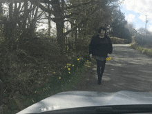 a woman is walking down a road holding flowers