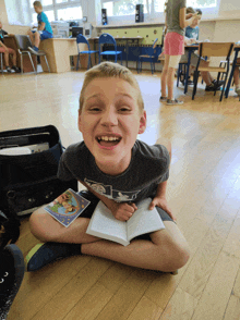 a young boy is sitting on the floor reading a book and laughing