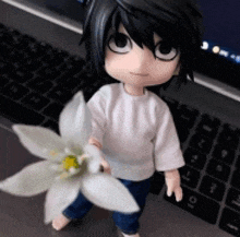 a doll holding a flower in front of a laptop