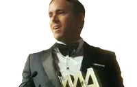 a man in a tuxedo is holding a trophy that says aaa