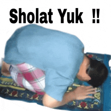 a man in a blue shirt is praying on a blue blanket with the words sholat yuk !! above him