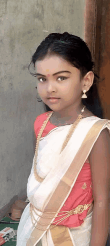 a little girl wearing a white and gold dress and earrings