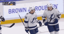 two hockey players are standing on the ice in front of a sign that says " brown & rouen "