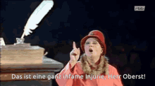 a woman in a red hat is pointing up and says das ist eine ganz infame injurie herr oberst