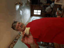 a man in a red shirt holds a piece of bread