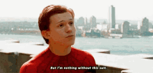 a young man in a spiderman suit is sitting on a balcony and talking to someone .