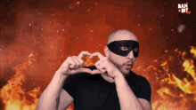 a man wearing a black mask making a heart shape