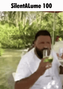 a man with a beard is drinking a glass of wine while sitting on a table .