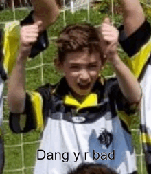 a young boy in a soccer uniform is holding his hands in the air .