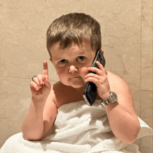 a child wrapped in a towel is talking on a cell phone