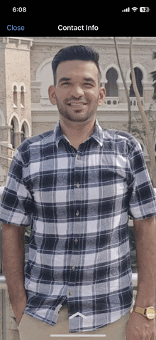 a man in a plaid shirt stands in front of a building with contact info displayed