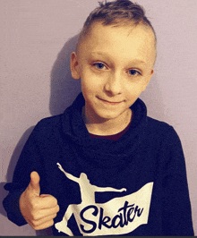 a young boy giving a thumbs up wearing a skater sweatshirt