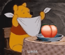 winnie the pooh is sitting at a table holding a towel around his neck and a peach on a plate .