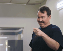 a man wearing a valley t-shirt is pointing at the camera