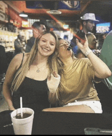 two women are sitting at a table with a drink and a straw