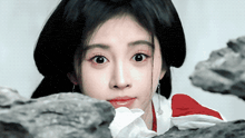 a close up of a woman 's face with a rock in the background
