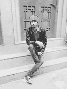 a black and white photo of a man sitting on steps