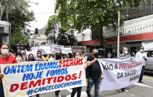 a group of people march down a street holding a banner that says ontem eramos herois hoje fomos demitidos