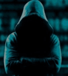 a man in a hooded sweatshirt with his arms crossed is standing in the dark .