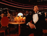 a man in a tuxedo is covering his face with his hands