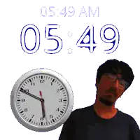 a man stands next to a clock that says 5:49 am