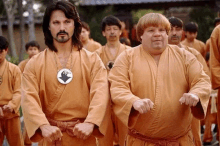 a group of men wearing orange karate uniforms are standing in a line