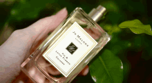 a person is holding a bottle of jo malone lotus flower cologne