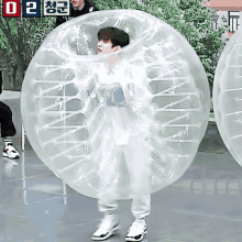 a young man is standing inside of a clear plastic bubble .