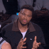 a man wearing glasses is making a funny face with his hands