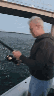 a man in a black jacket is fishing in the ocean