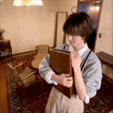 a person holding a book in a room with chairs and a table